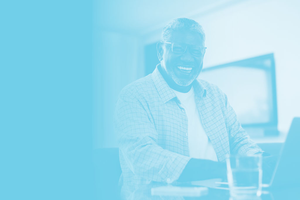 Man smiling while working on a laptop